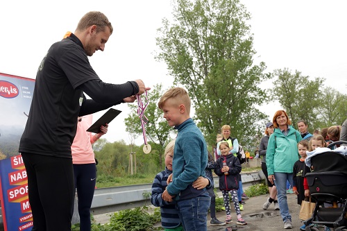 Michal Burian, hlavní organizátor Běhu pro Zoo Praha, předává mediali jednomu z vítězů dětského závodu